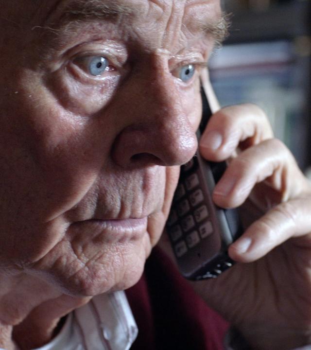 Nachgestellte Szene: Ein älterer Herr ist am Telefon. Sein Blick ist fassungslos.