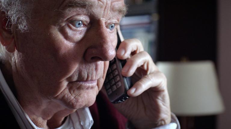 Nachgestellte Szene: Ein älterer Herr ist am Telefon. Sein Blick ist fassungslos.