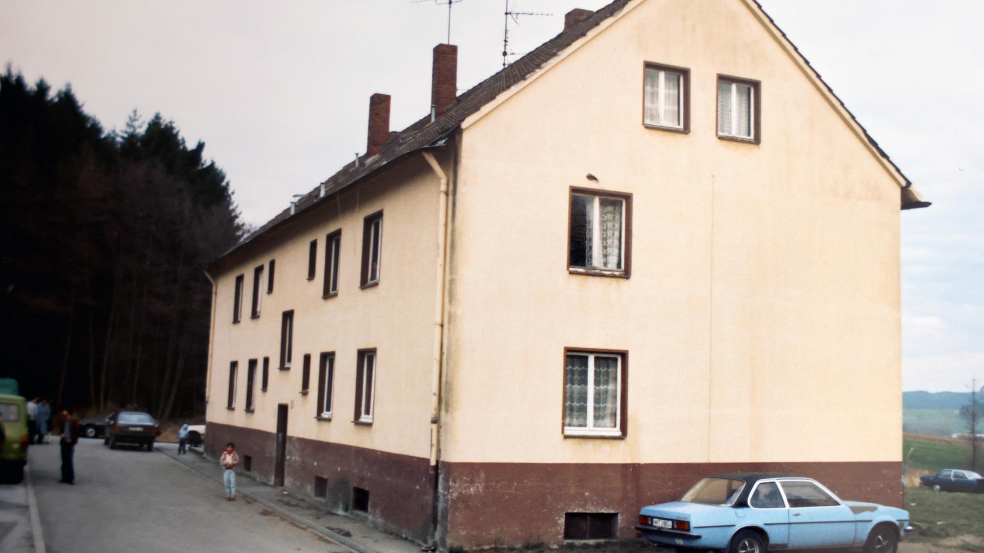 Foto des Hauses von Zeyneps Familie: Ein Mehrparteienhaus aus den 80er-Jahren, gelb gestrichen mit braunem Sockel und Satteldach.