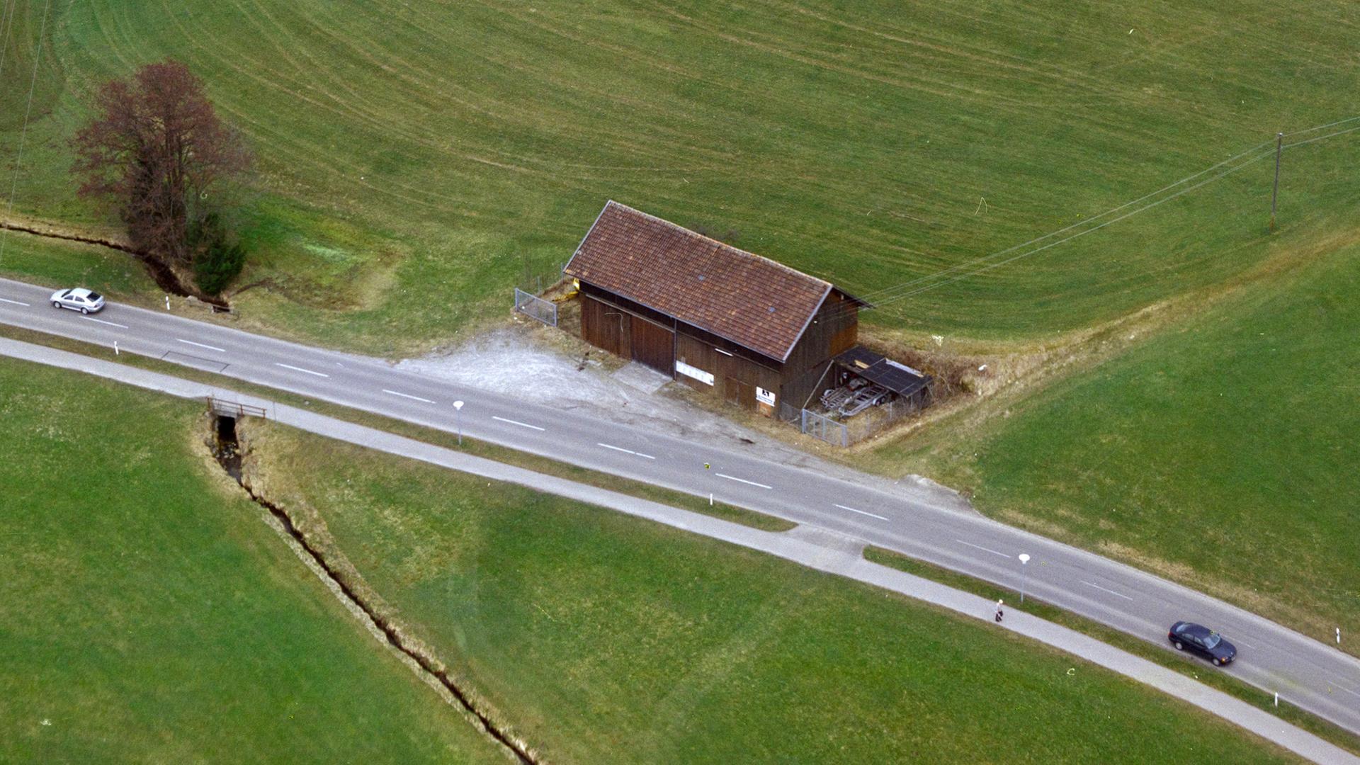 Ein Heuschober nahe Heiligkreuz bei Kempten aus der Luft. Eine Straße führt vor ihm vorbei.