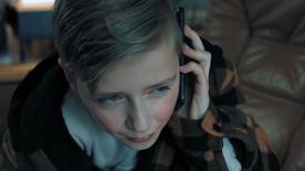 Escena reconstruida: un niño pequeño se acerca un teléfono inteligente a la oreja mientras llora.