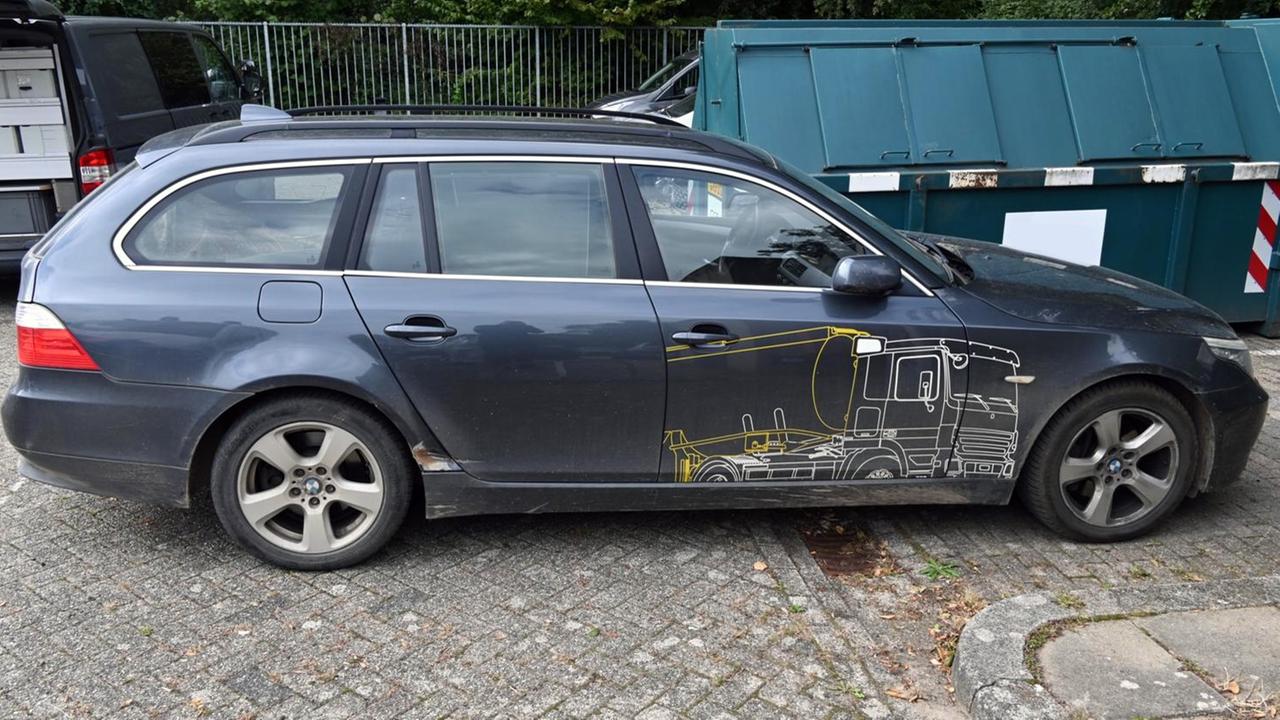 Ein dunkelgrauer Kombi mit einem aufgemalten gelb-weißen Lkw