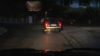 Nachgestestellte Szene: Eine junge Frau steht an einem Auto.