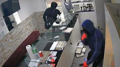 Zwei Männer verlassen nach dem Raub hastig das Juweliergeschäft.