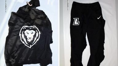 Eine schwarze Trainingsjacke mit weißem Löwenkopf auf dem Rücken und eine Trainingshose mit dem weißen Buchstaben „L“