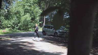 Nachgestellte Szene: Eine Frau in Sportkleidung joggt auf einem Parkplatz im Wald.