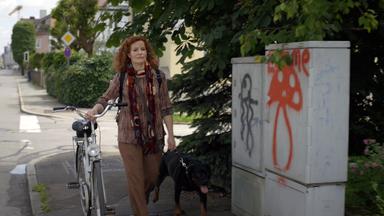 Nachgestellte Szene: Jutta Schulz geht mit ihrem Hund und ihrem Fahrrad die Straße entlang.