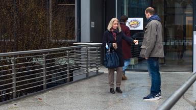 Nachgestellte Szene: Eine Frau und ein Mann stehen sich gegenüber. Sie gibt ihm einen Zettel.