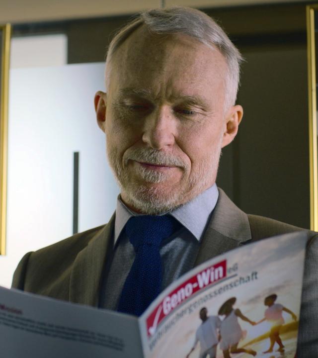 XY-Szenenfoto: Ein älterer Mann informiert sich in einer Fachbroschüre über Genossenschaftsinvestitionen im Ausland.