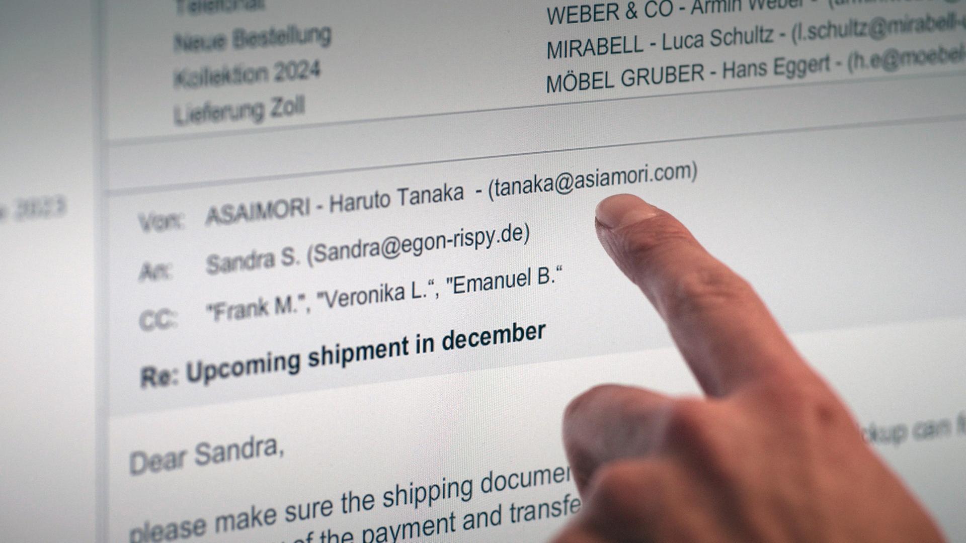 XY-Szenenfoto: Ein Zeigefinger weist auf einem Computerbildschirm auf die Absender-Adresse einer E-Mail.