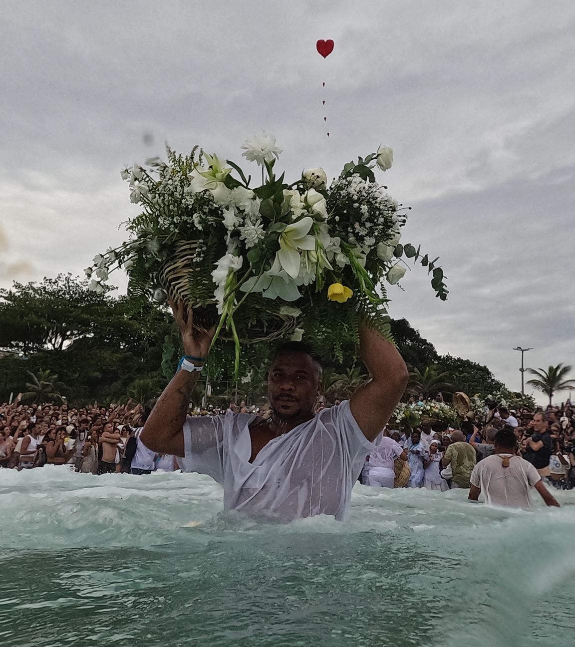 Ein Mann hält einen traditionellen Blumenkorb auf dem Kopf und trägt in ins Meer