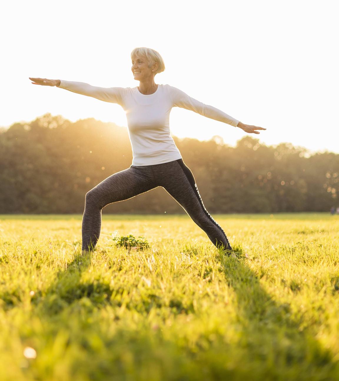Frau macht Yoga auf einer Wiese.