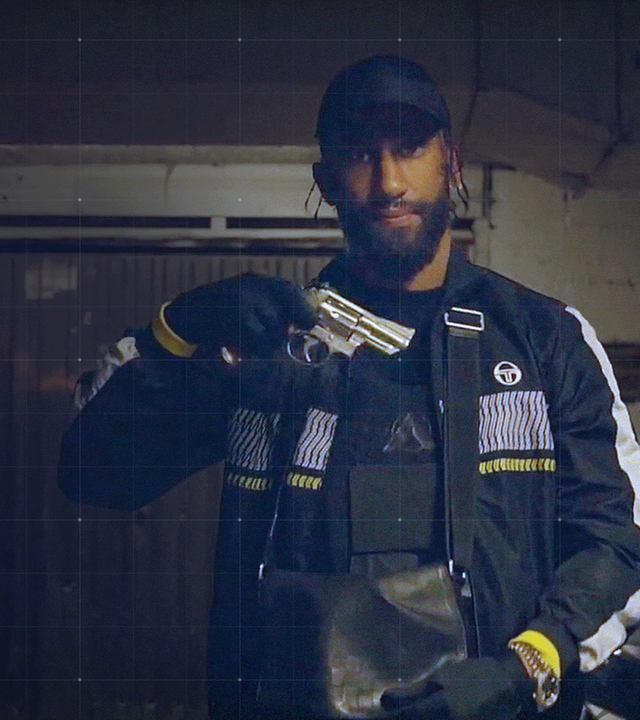 Omar Chehade aka Gomorra, der über seine kriminelle Vergangenheit rappt, mit Pistole in der Hand vor Garagentor und Motorroller im Hintergrund