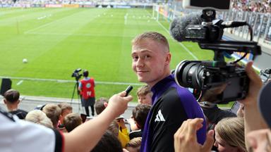 Youtuber Marvin Wildhage steht während des öffentlichen Trainings in Jena auf der Tribüne.