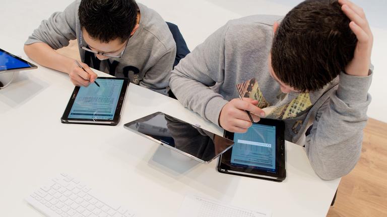 Zwei Schüler, welche mit ihren Tablets für die Schule lernen.