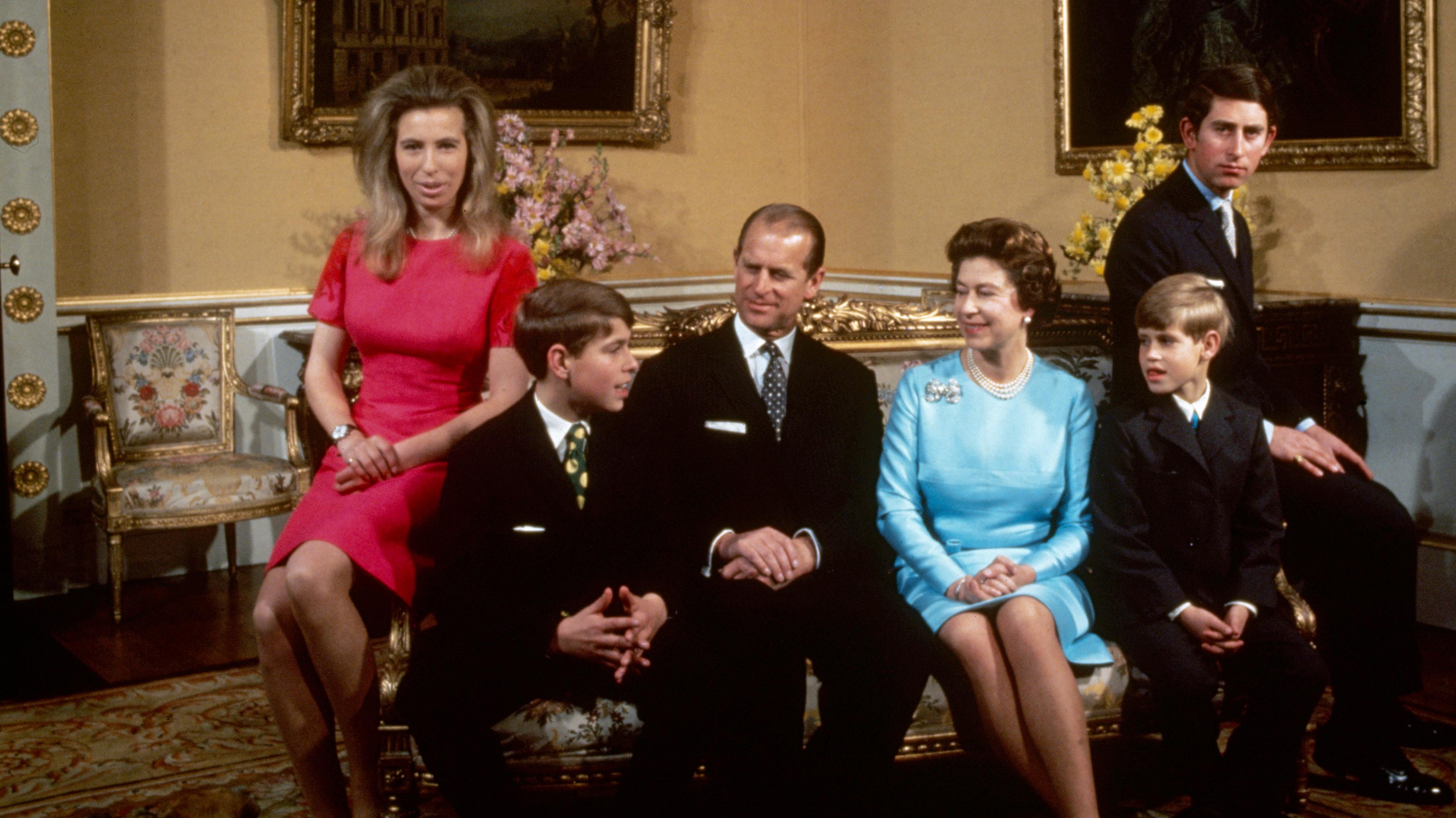 Die britische Königsfamilie rund um Queen Elizabeth II. ist auf dem Bild zu sehen. Charles und Anne auf den Armlehnen der Couch, Andrew und Edward neben ihren Eltern Philip und Elizabeth.
