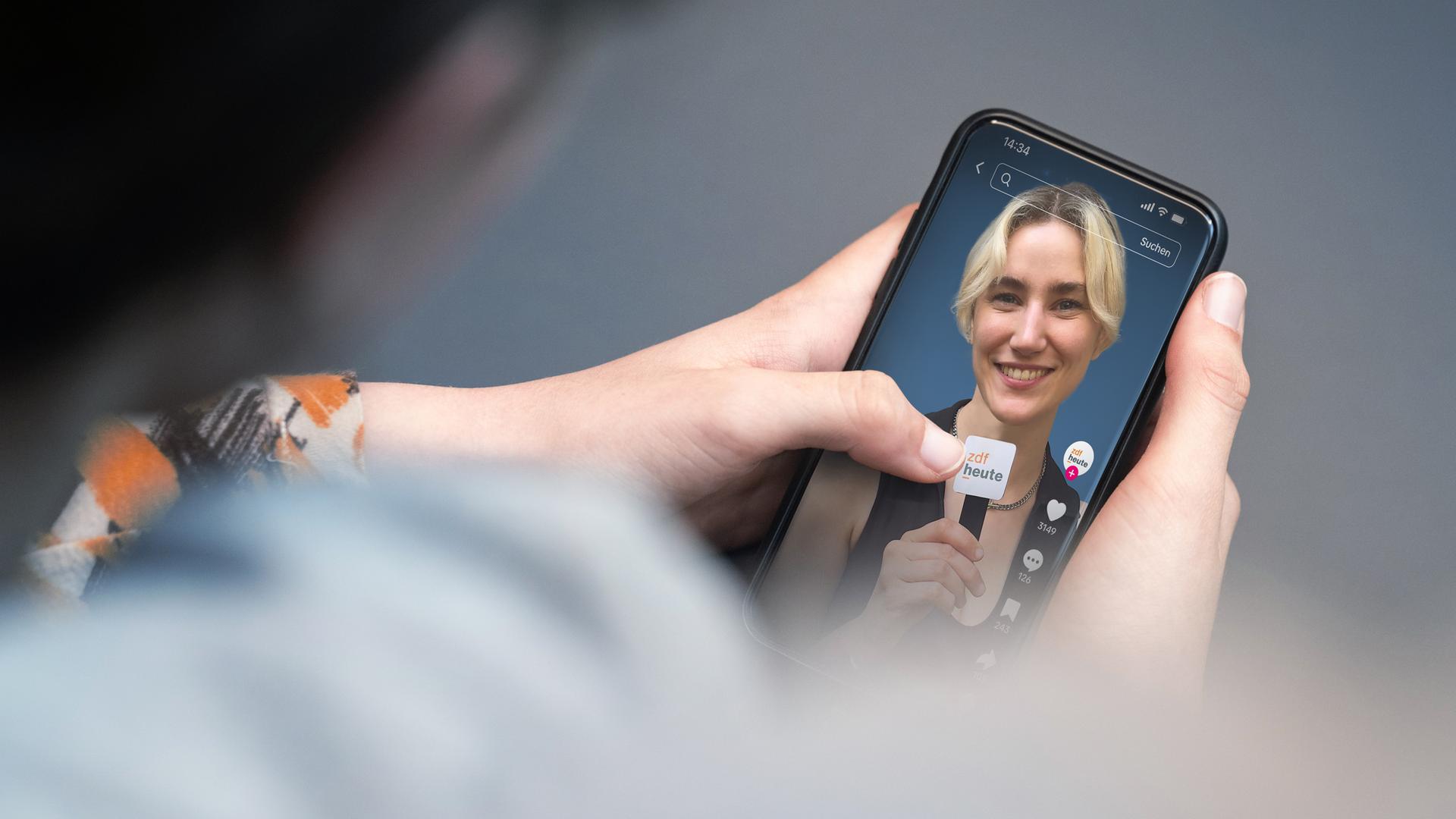 Eine Person hält ein Smartphone in der Hand, auf dem der TikTok-Kanal der ZDFheute zu sehen ist. 
