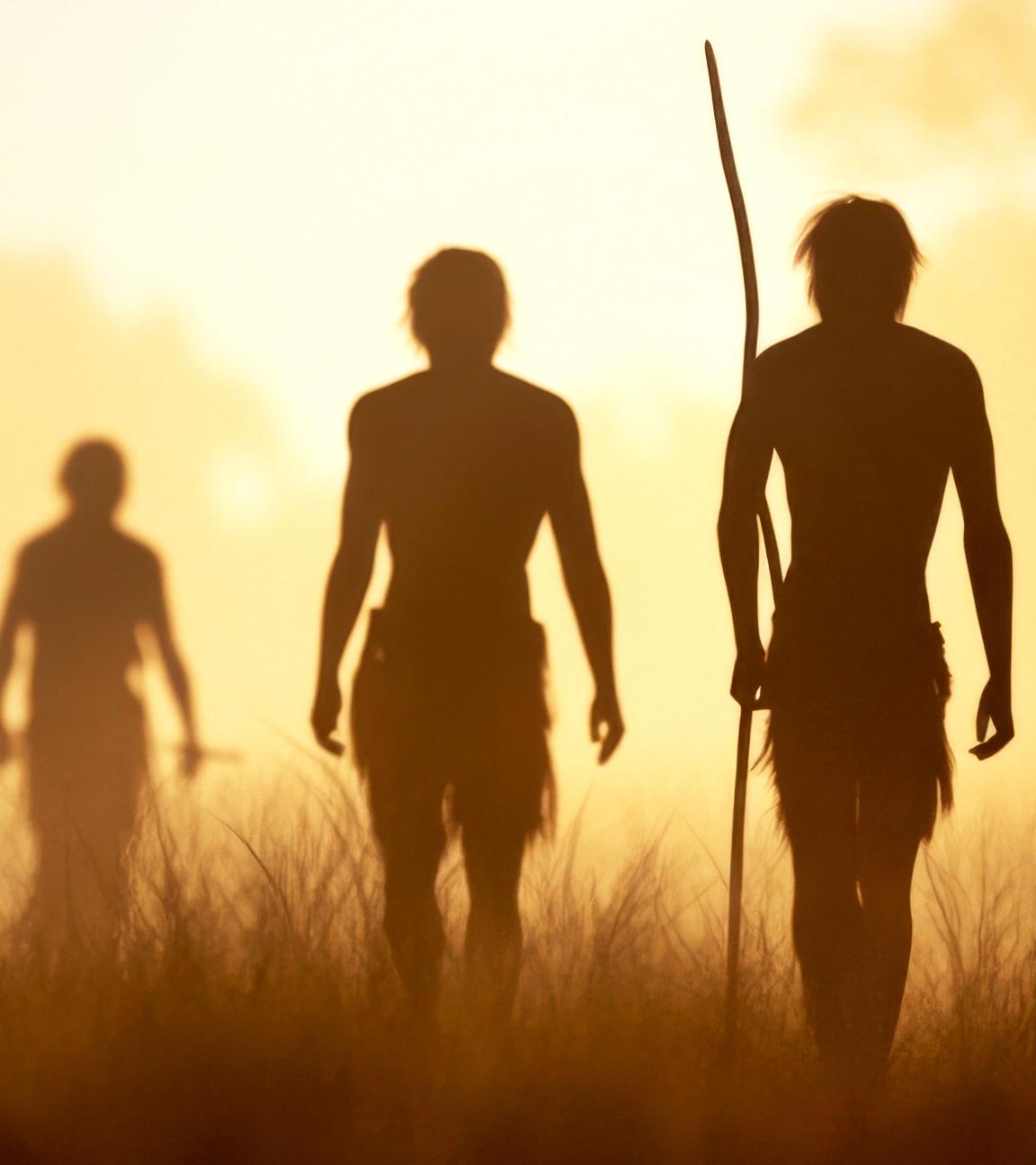 Eine Gruppe Urzeitmenschen in der Steppe, im Gegenlicht sind nur ihre Konturen zu erkennen