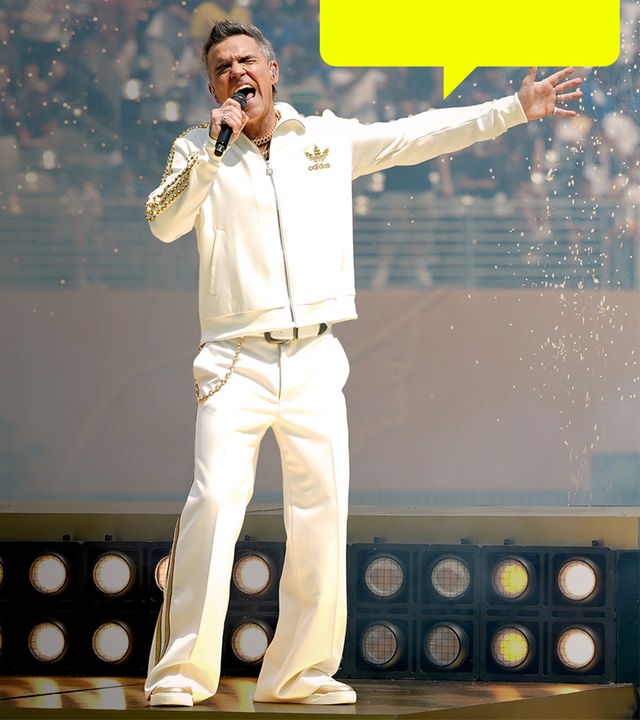 Robbie Williams performt in weißem Anzug auf der Bühne.