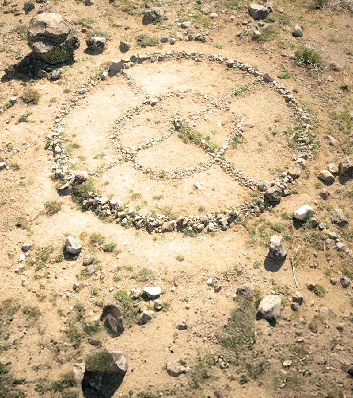 Rechts das mit Steinen geformte Signet des Zodiackillers. Links das Phantombild des Zodiackillers auf einem Stapel alter Bilder, dahinter in rot sein Zeichen