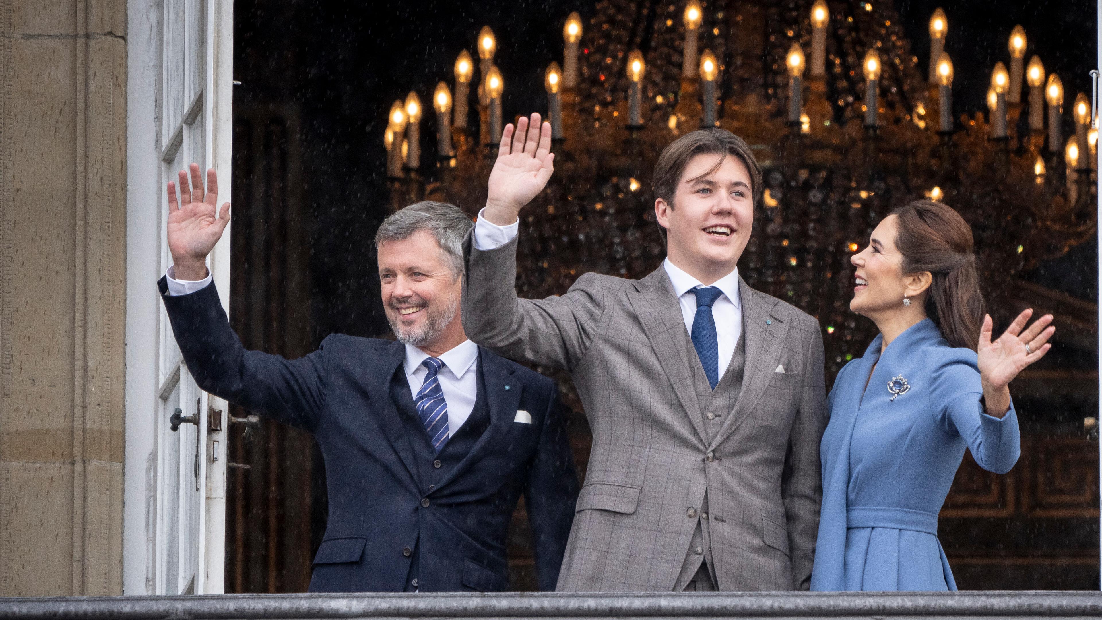 Der dänische König Frederik und seine Frau Mary stehen mit Christian in der Mitte auf dem Balkon und winken.