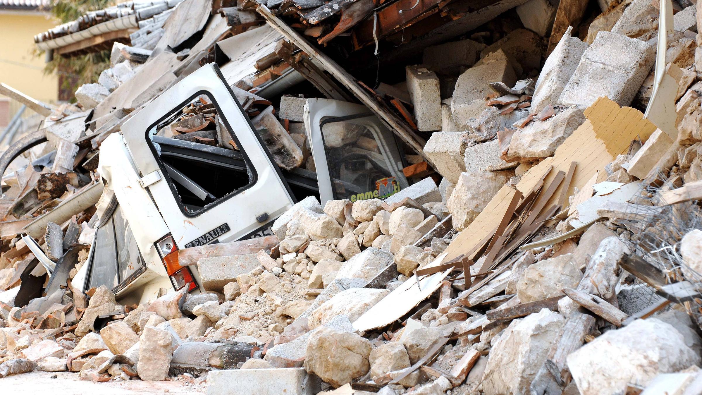 Ein Auto ist unter den Trümmern eines eingestürzten Hauses in L'Aquila begraben
