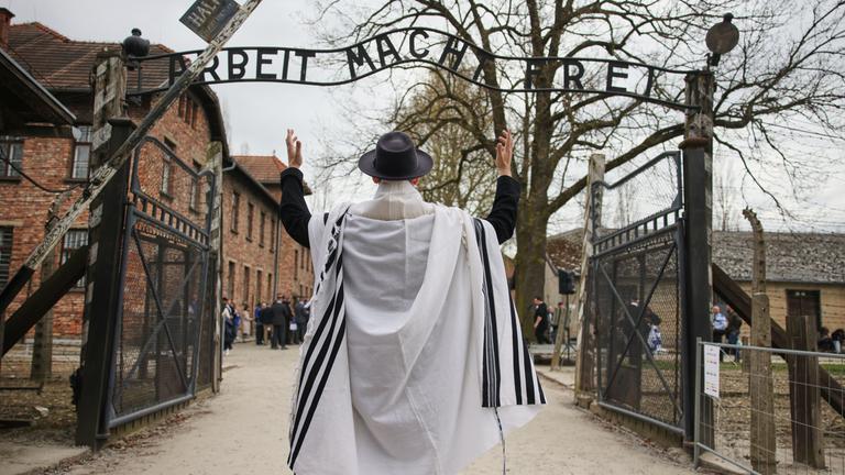 Ein Mann steht vor dem Eingang von Auschwitz zum jährlichen "Marsch der Lebenden", einem jährlichen Gedenkmarsch zwischen den ehemaligen Vernichtungslagern Auschwitz und Birkenau