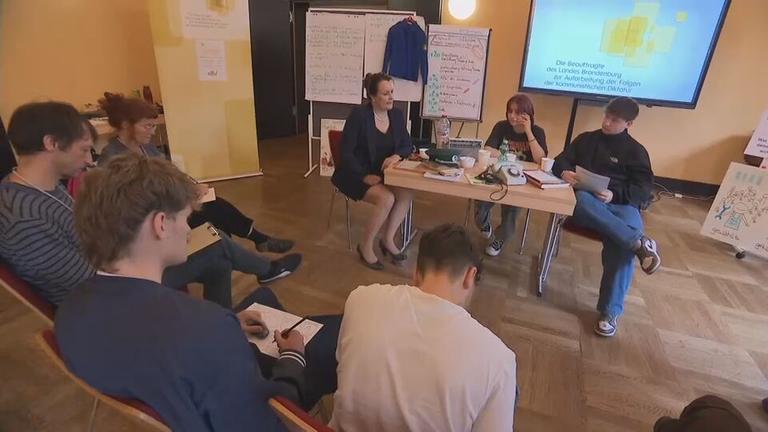 Menschen sitzen gemeinsam in einem Zeitzeugen-Workshop über die DDR-Zeit und Wiedervereinigung.