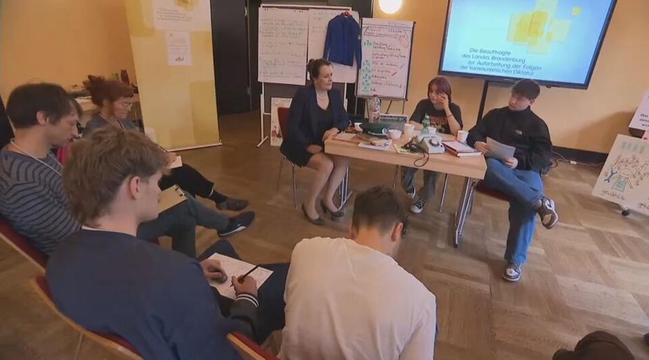 Menschen sitzen gemeinsam in einem Zeitzeugen-Workshop über die DDR-Zeit und Wiedervereinigung.