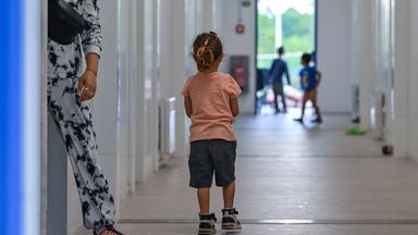 Ein kleines Mädchen steht auf dem Flur von Wohncontainern für Migranten auf dem Gelände der Zentralen Erstaufnahmeeinrichtung für Asylbewerber (ZABH) des Landes Brandenburg. 