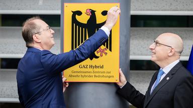 Alexander Dobrindt (CSU, l), Bundesinnenminister, schraubt im Beisein von Sinan Selen, Präsident des Bundesamtes für Verfassungsschutz, posieren symbolisch bei der Einweihung des Gemeinsamen Zentrums zur Abwehr hybrider Bedrohungen das entsprechende Schild an. 