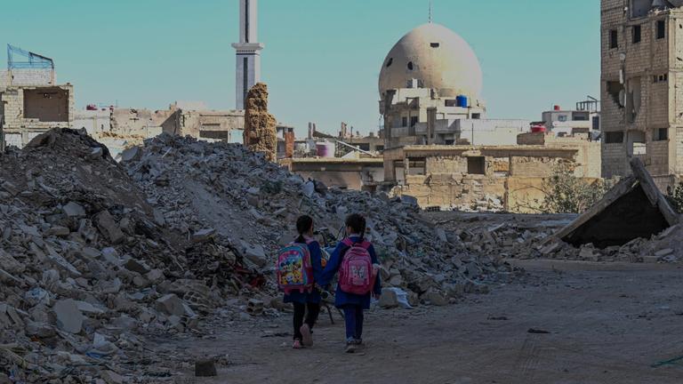 Syrische Kinder laufen am 29. 10. 2025 durch die Trümmer zerstörter Gebäude in Daraya am Stadtrand von Damaskus. 
