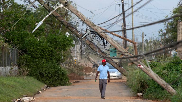 Eine Person geht  in Santa Cruz, Jamaika eine Straße entlang, die vom Hurrikan Melissa betroffen ist.