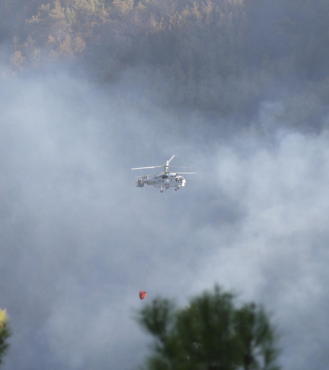 Ein Helikopter fliegt über ein von Waldbränden betroffenes Gebiet im türkischen Antalya