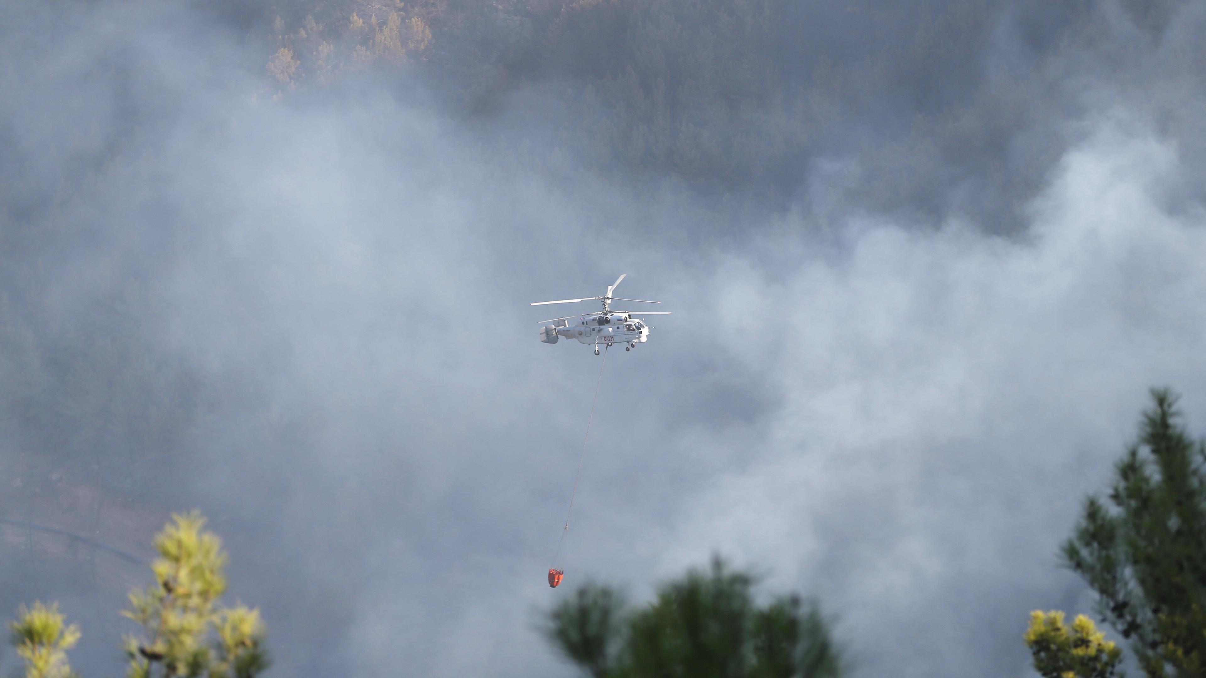 Ein Helikopter fliegt über ein von Waldbränden betroffenes Gebiet im türkischen Antalya