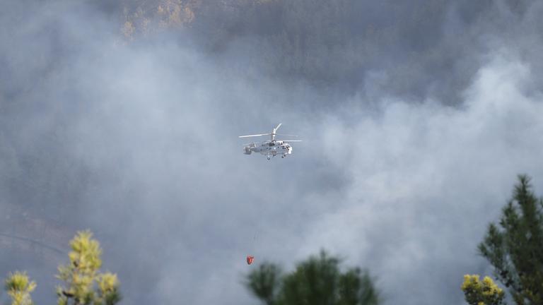 Ein Helikopter fliegt über ein von Waldbränden betroffenes Gebiet im türkischen Antalya