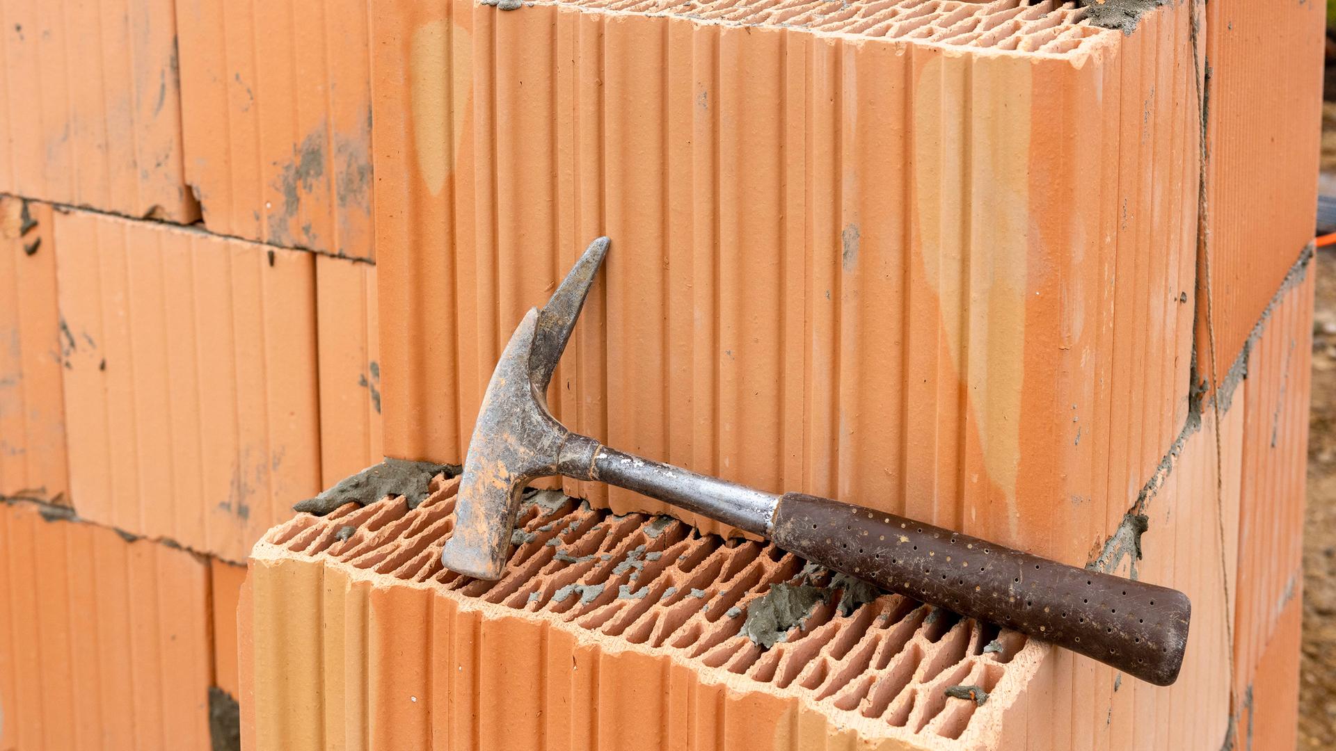 Zimmermannshammer liegt auf einem Ziegel eines Neubaus