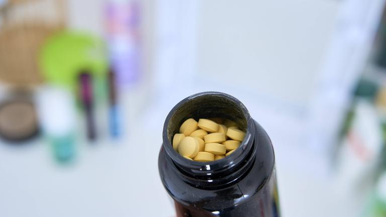Eine geöffnete schwarze Dose mit gelben Tabletten.