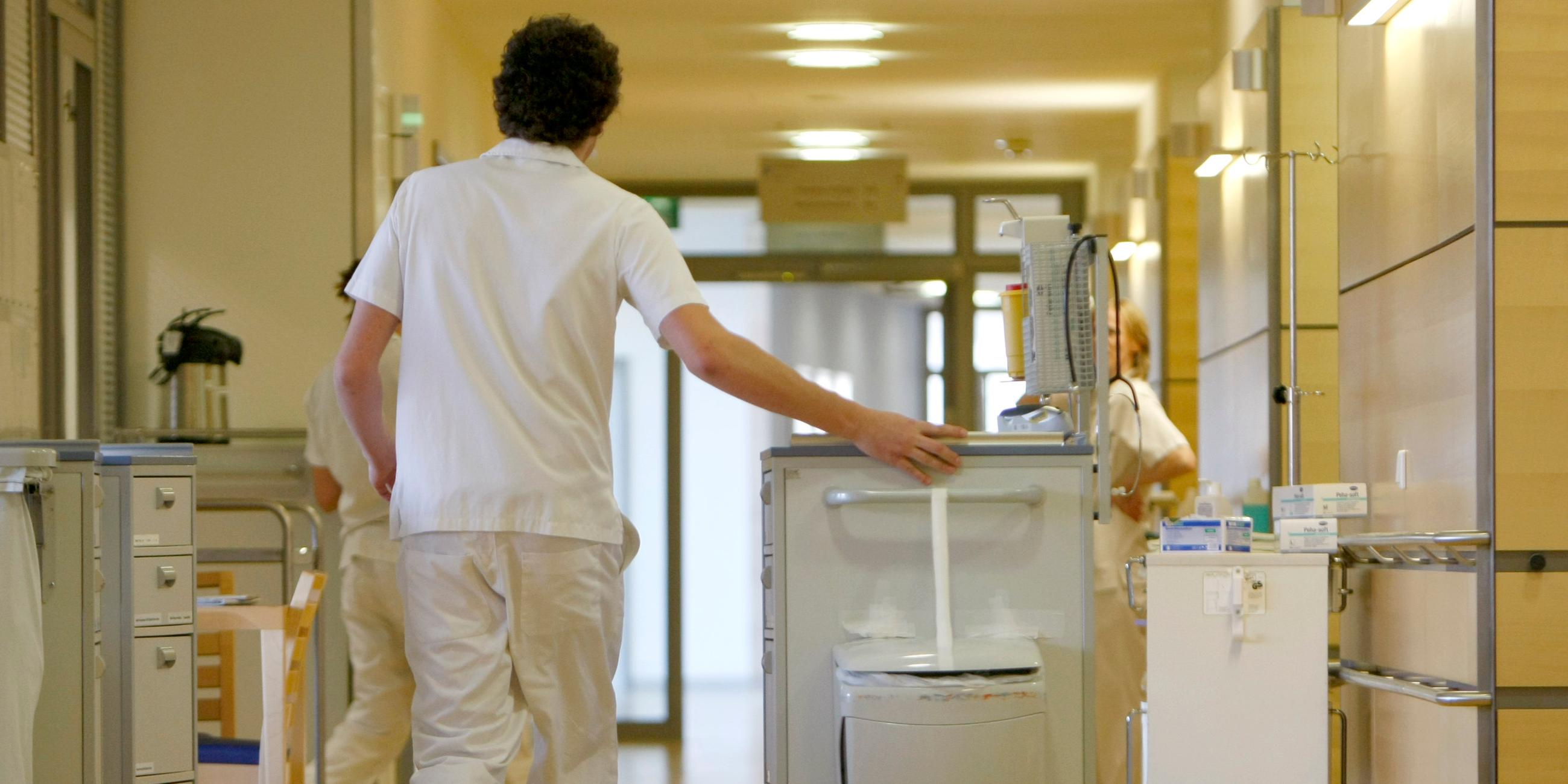 Ein Zivildienstleistender schiebt einen Medikamentenwagen über einen Flur in einem Krankenhaus