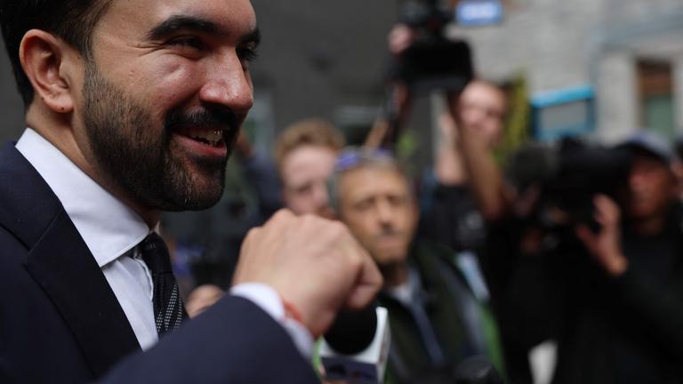 Zohran Mamdani lächelnd vor eine Gruppe Journalisten