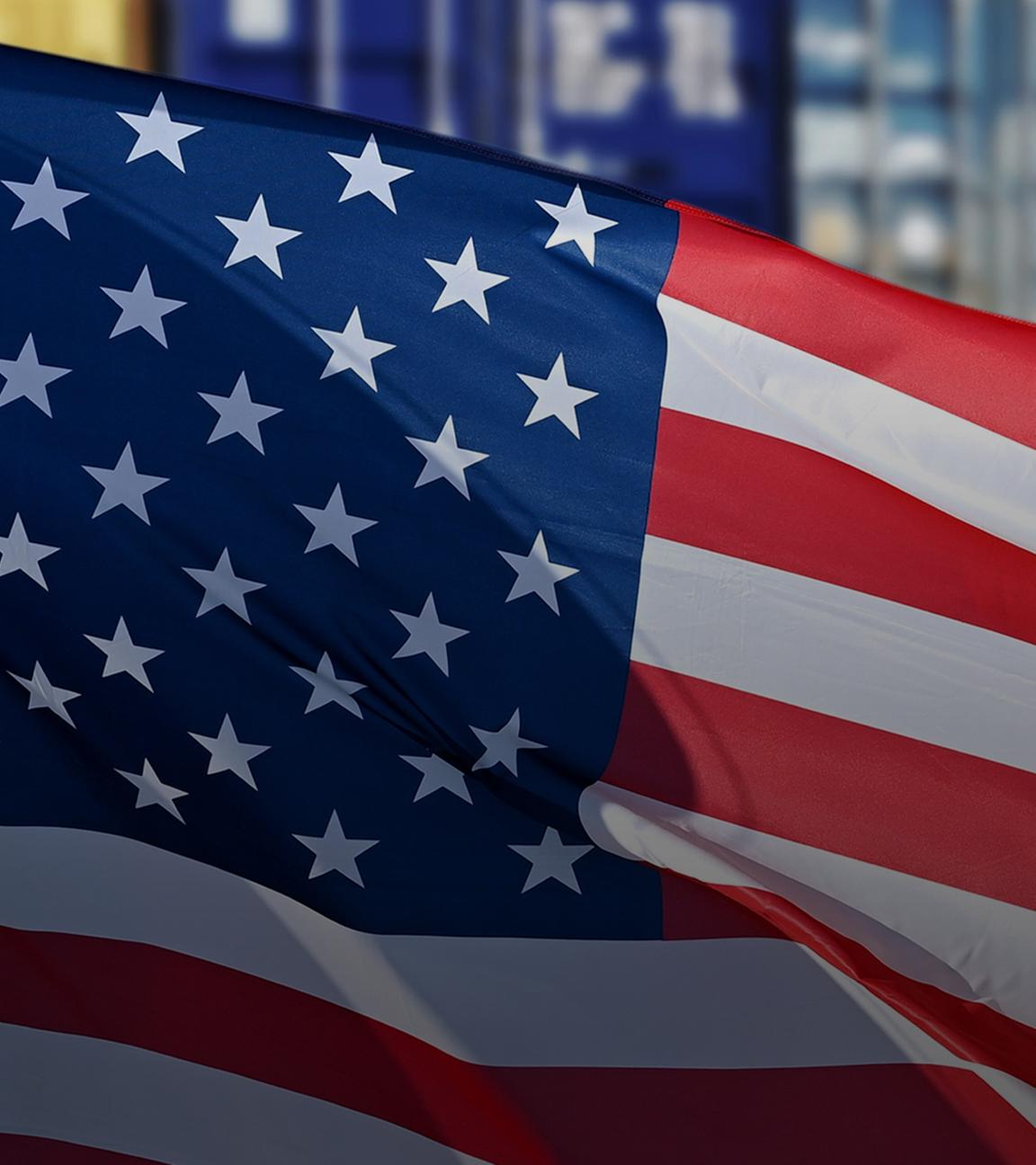 Wehende amerikanische Flagge vor aufgestapelten Containern