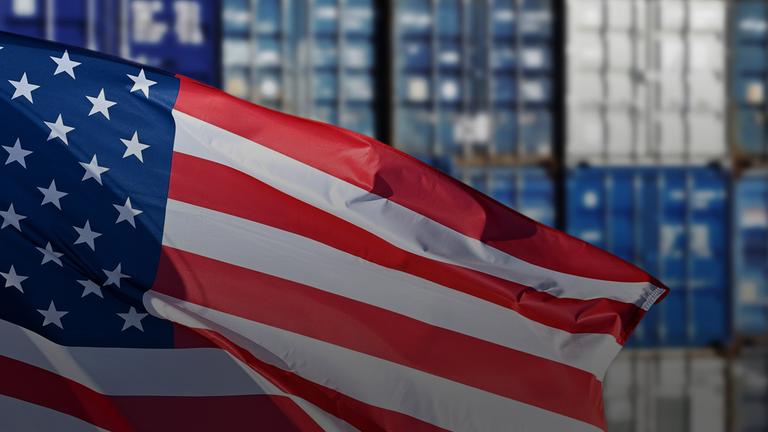 Wehende amerikanische Flagge vor aufgestapelten Containern