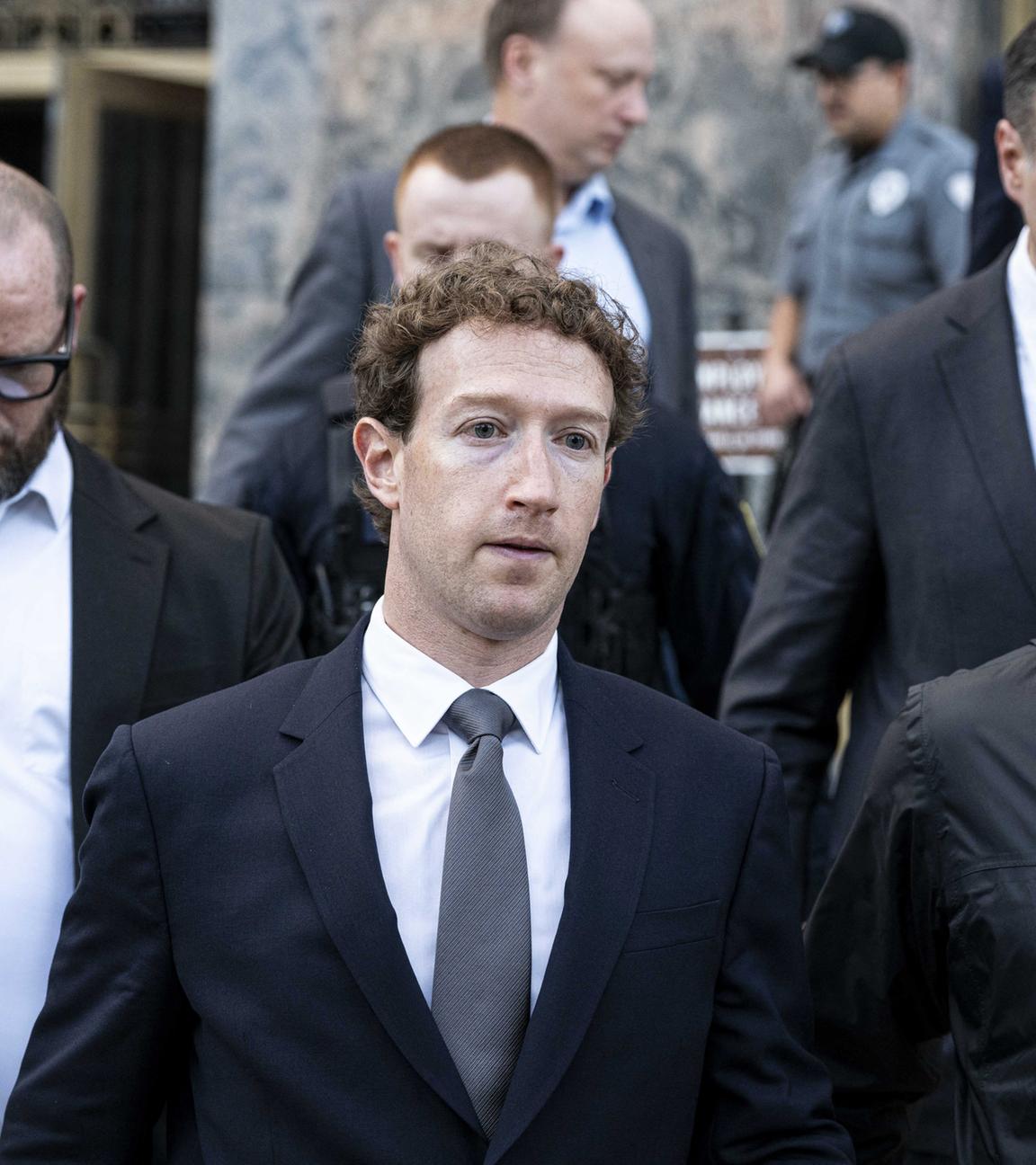 Meta CEO Mark Zuckerberg verlässt einen Gerichtssaal in der Mitte zwischen zwei Personen.