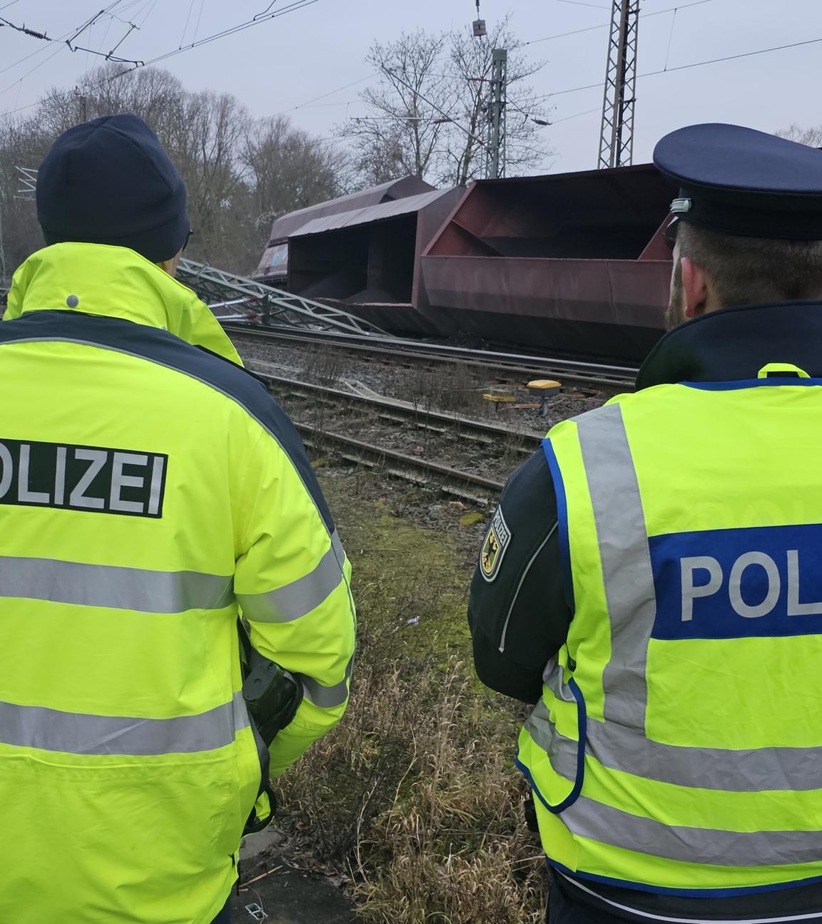 Niedersachsen, Elze: Einsatzkräfte der Bundespolizei stehen an den Gleisen neben umgekippten Schüttgutwagen.