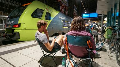 Reisende sitzen am Bahnsteig im Hamburger Hauptbahnhof