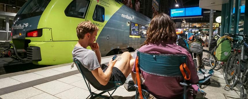 Reisende sitzen am Bahnsteig im Hamburger Hauptbahnhof