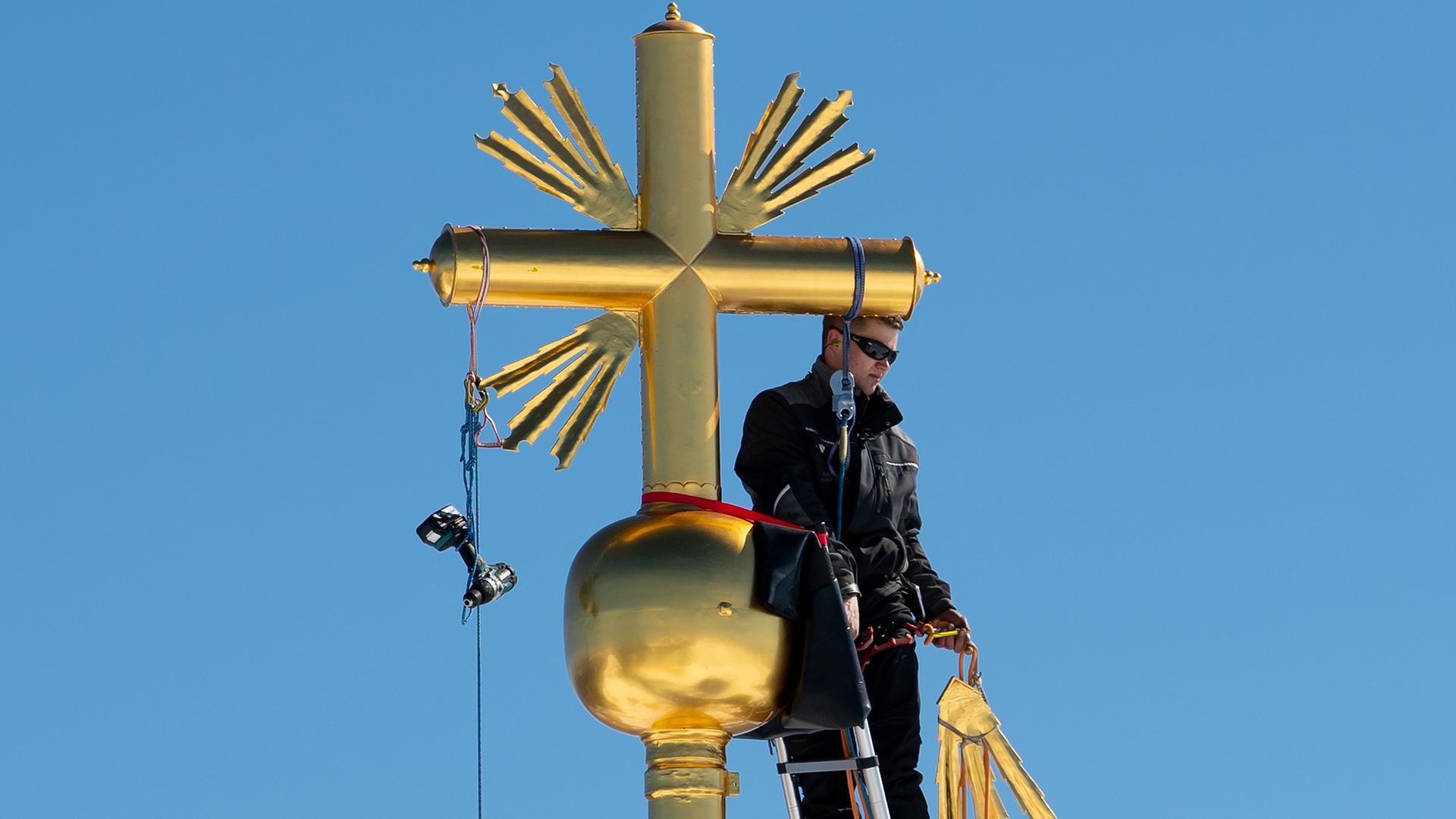 Bayern, Garmisch-Partenkirchen: Johannes Wagner (l), Schlosser, und Andreas Grünauer reparieren das Gipfelkreuz auf der Zugspitze. Archivbild