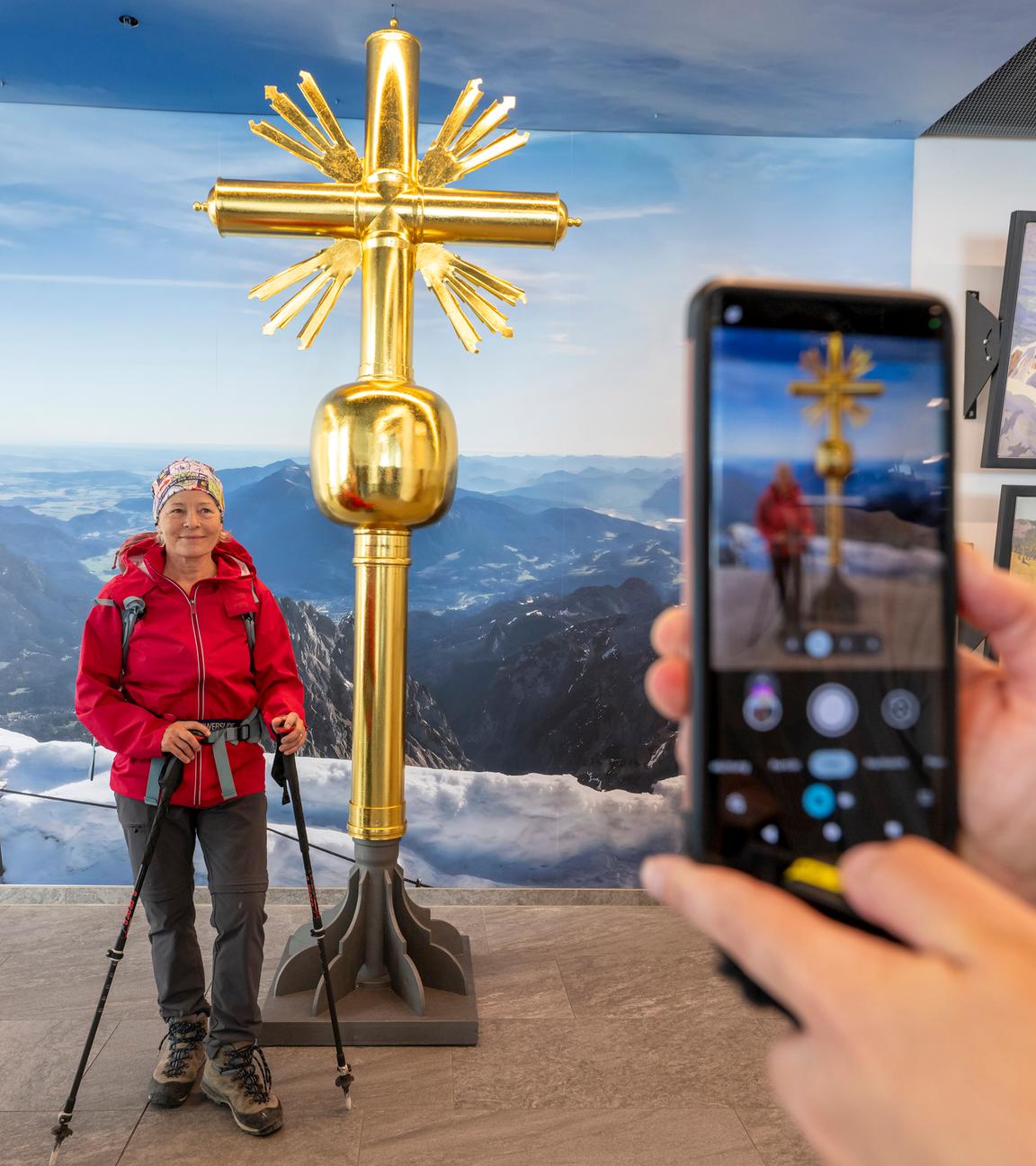 Eine Wanderin lässt sich vor dem 2. Gipfelkreuz auf der Zugspitze fotografieren.