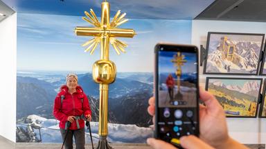 Eine Wanderin lässt sich vor dem 2. Gipfelkreuz auf der Zugspitze fotografieren.
