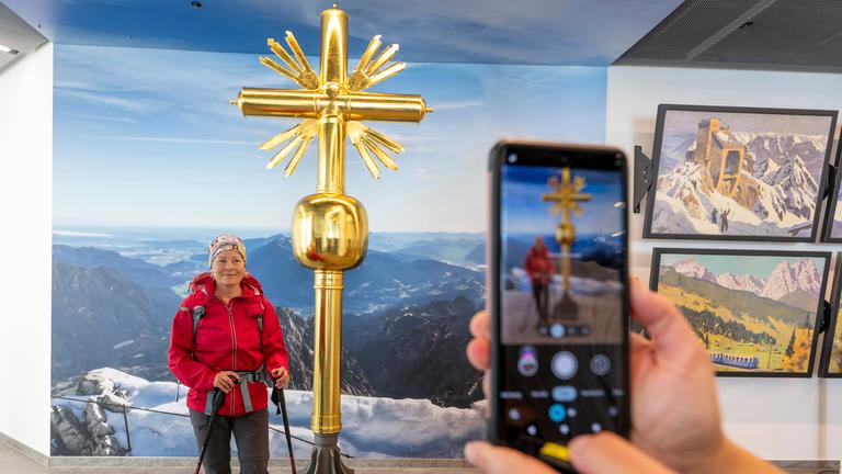 Eine Wanderin lässt sich vor dem 2. Gipfelkreuz auf der Zugspitze fotografieren.